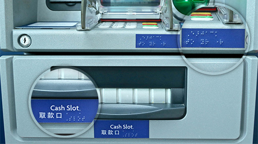 Braille characters indicate the location of the audio jack as well as the cash slot, to help the customer identify necessary features on the machine.